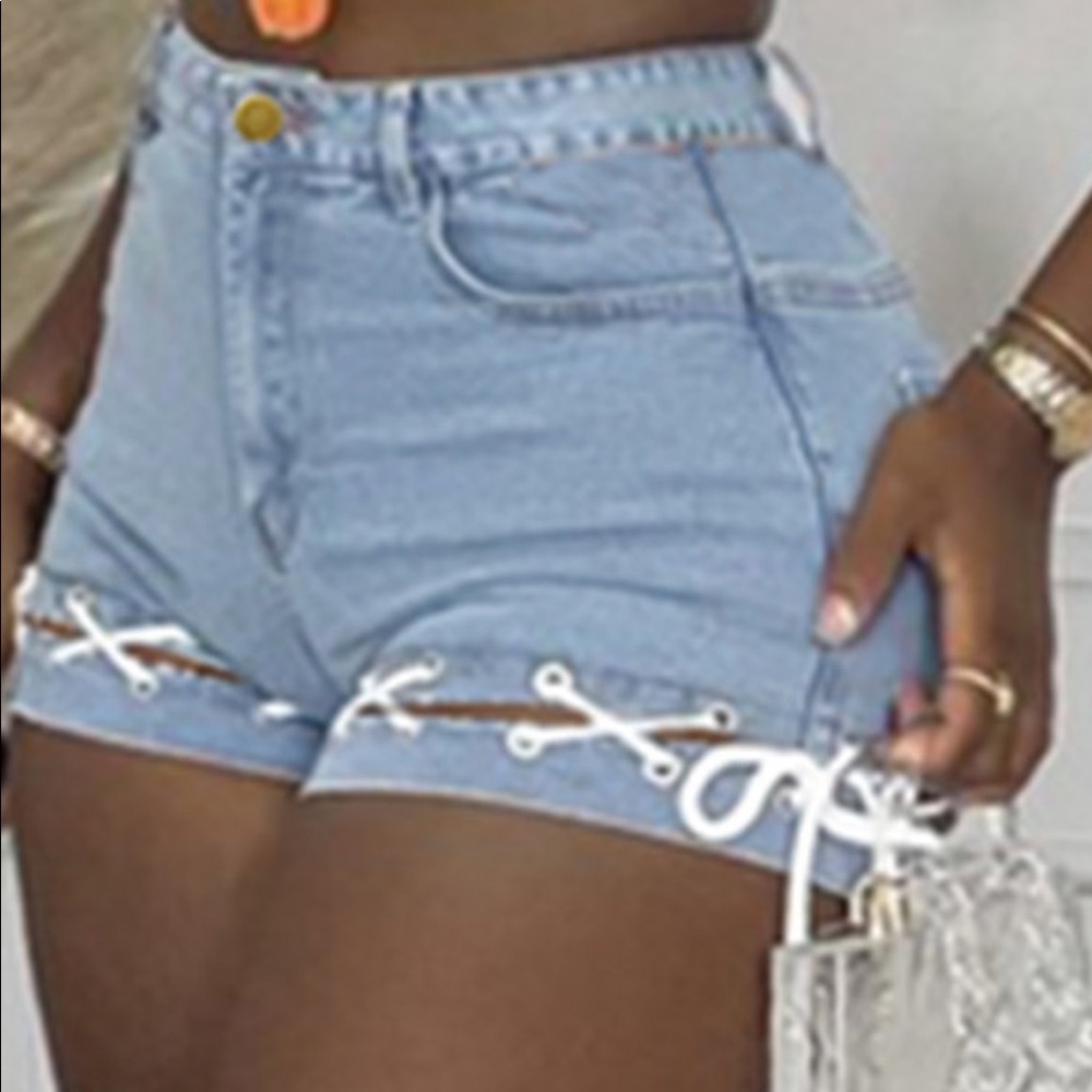 Denim shorts with white strings connecting the bottom light wash